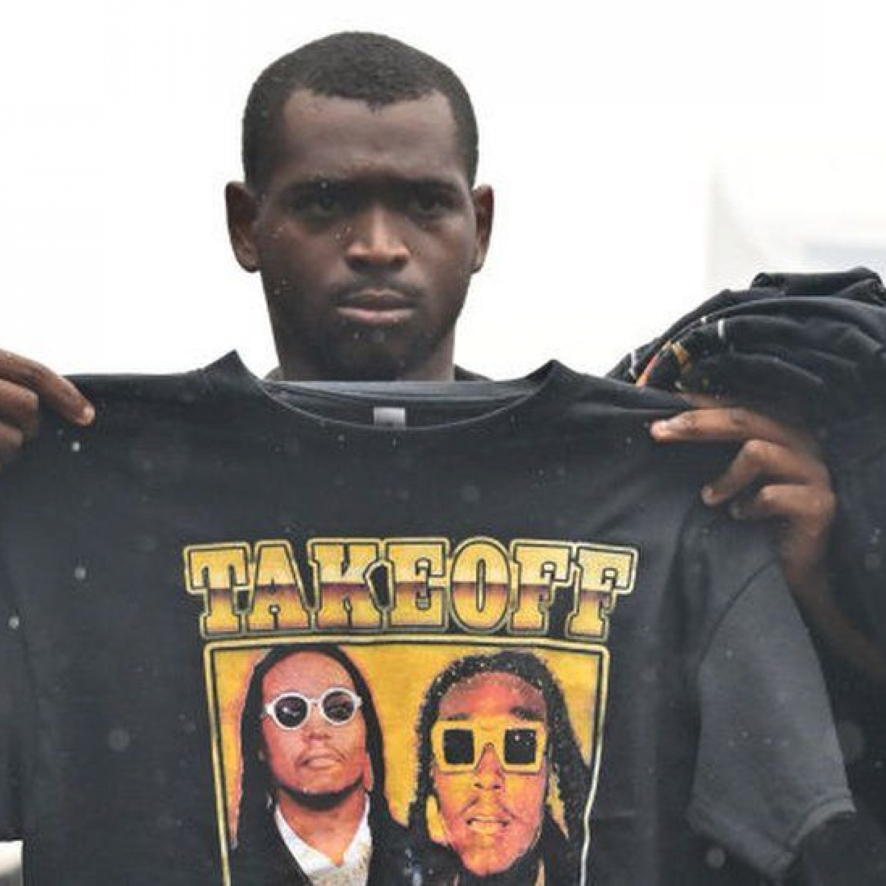 A fan holds up a shirt honouring Takeoff as he stands in linefor the memorial service