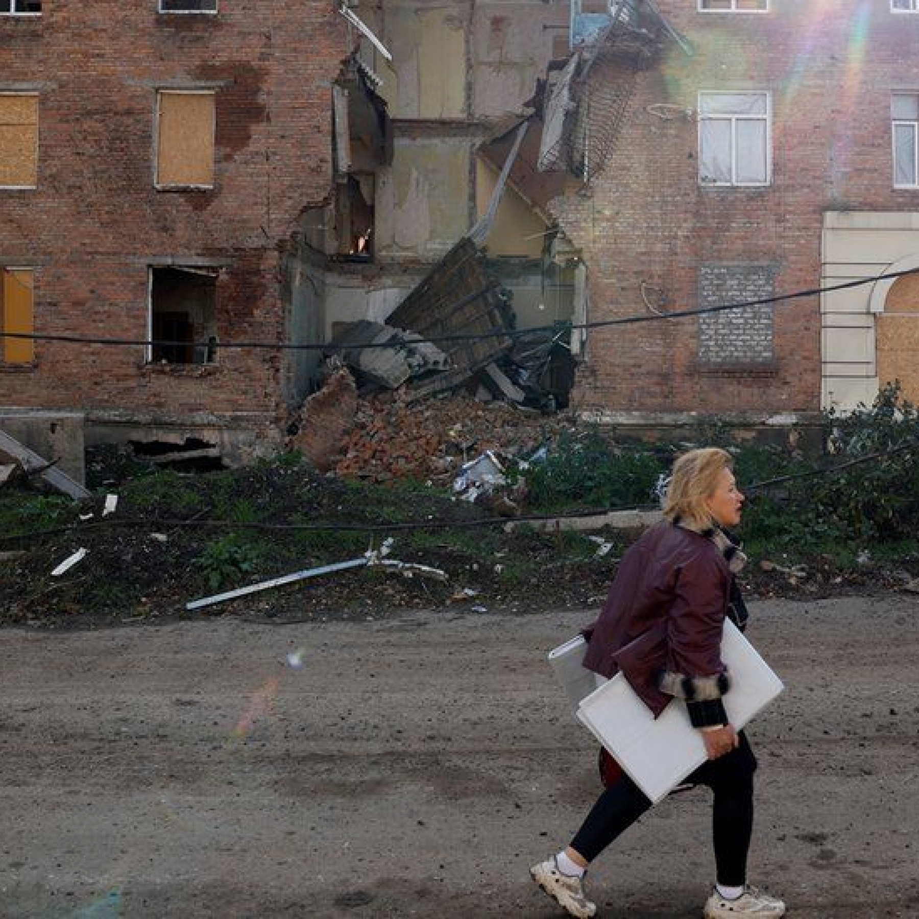A woman walks past a building damaged by missile strikes in the eastern Donbas region of Bakhmut, Ukraine