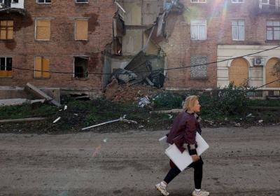 A woman walks past a building damaged by missile strikes in the eastern Donbas region of Bakhmut, Ukraine